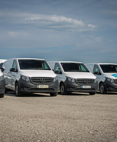 Mehrere weiße Mercedes-Benz Transporter parken in einer Reihe.