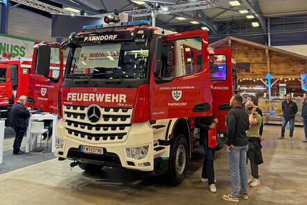 Ein Feuerwehr-Lkw der Freiwilligen Feuerwehr Parndorf bei einer Messe ausgestellt, mit dem Logo von Pappas im Hintergrund.