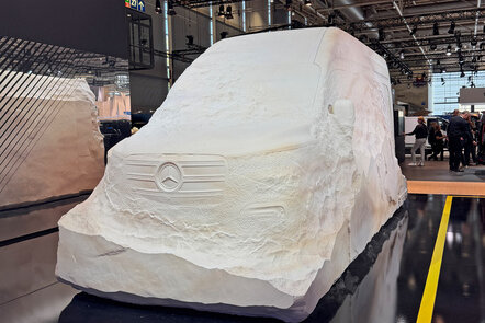 Skulptur eines Mercedes-Benz Vans aus Stein auf einer Messe.