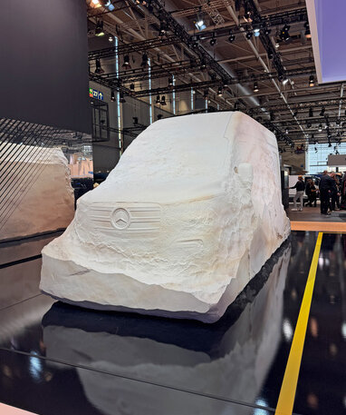 Skulptur eines Mercedes-Benz Vans aus Stein auf einer Messe.