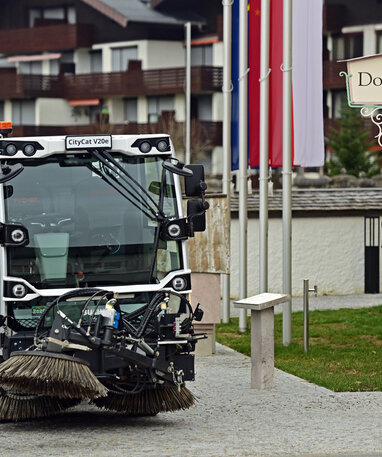 Eine Straßenkehrmaschine der Marke CityCat vor einem Schild mit der Aufschrift 'Dorfplatz'.