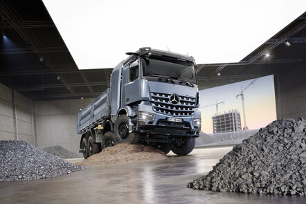 Ein silberner LKW steht auf einem Sandhügel in einer Halle, umgeben von Kieshaufen. | © Daimler Truck AG