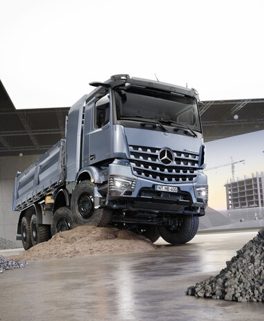Ein silberner LKW steht auf einem Sandhügel in einer Halle, umgeben von Kieshaufen. | © Daimler Truck AG
