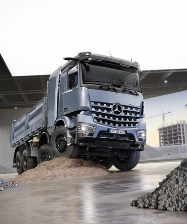 Ein silberner LKW steht auf einem Sandhügel in einer Halle, umgeben von Kieshaufen. | © Daimler Truck AG