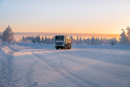 Ein eArocs400 fährt bei Sonnenuntergang auf einer verschneiten Straße durch eine winterliche Landschaft.