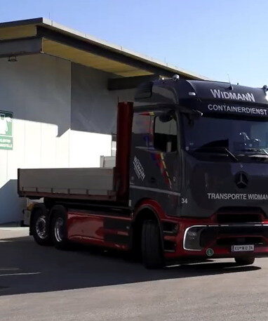 Der elektrische Lkw eActros von Mercedes-Benz aus dem Fuhrpark der Firma Widmann steht vor einer Ladestation.