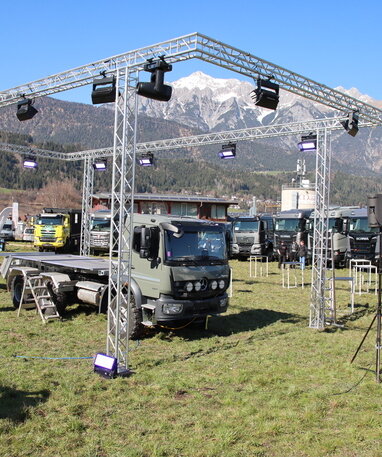Das Basisfahrzeug der ZirbenBOX steht unter einem Layer mit Scheinwerfern vor einer Bergkulisse.