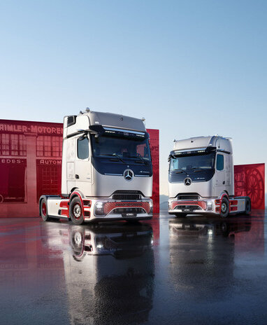 Zwei Mercedes-Benz Trucks stehen vor einem roten Container auf einer spiegelnden Fläche.