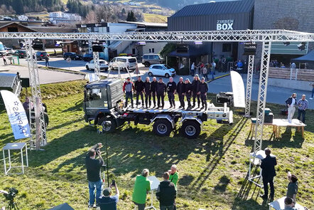 Gruppe von Menschen steht auf einem Lastwagen bei einer Veranstaltung im Freien.