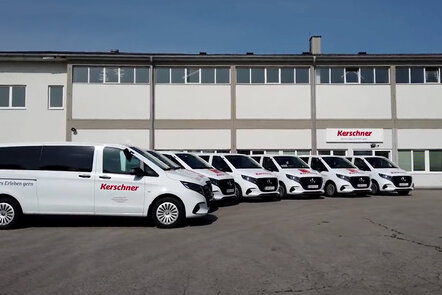 6 weiße Vito Tourer mit Kerschner-Branding stehen nebeneinander vor dem Kerschner Firmengebäude.