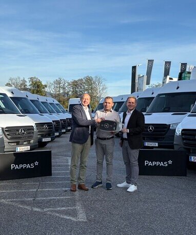 Johann Wieser und Rene Böckl von Pappas Eugendorf übergeben symbolisch einen großen Autoschlüssel an NA Logistik GmbH Inhaber Herrn Niazi. Im Hintergrund stehen mehrere weiße Mercedes-Benz Sprinter.