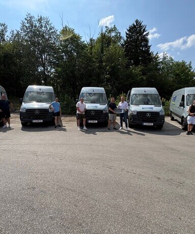 Fünf Personen posieren vor fünf neuen Mercedes-Benz Sprinter Kastenwagen.
