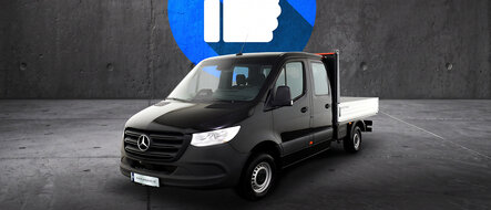 Ein schwarzer Mercedes-Benz Sprinter Pritschenwagen mit Doppelkabine vor grauem Hintergrund.