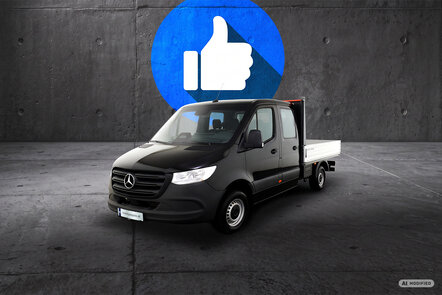 Ein schwarzer Mercedes-Benz Sprinter Pritschenwagen mit Doppelkabine vor grauem Hintergrund.