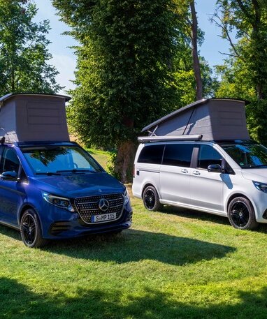 Zwei Mercedes-Benz Campingfahrzeuge mit ausfahrbarem Dach auf einer Wiese.