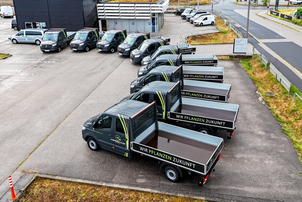 Reihe von Mercedes-Benz Sprinter Pritschenwagen mit der Aufschrift 'Wir pflanzen Zukunft'.