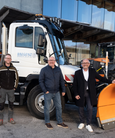 Vier Männer stehen vor einem weißen Unimog mit Schneepflug, bereit für den Winterdienst.