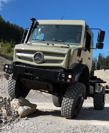 Ein geländegängiger Mercedes-Benz Unimog fährt über steiniges Terrain.