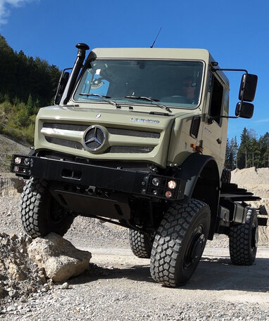 Ein geländegängiger Mercedes-Benz Unimog fährt über steiniges Terrain.
