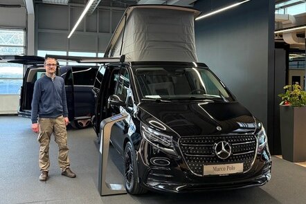 Mann steht neben einem schwarzen Mercedes Marco Polo im Showroom.