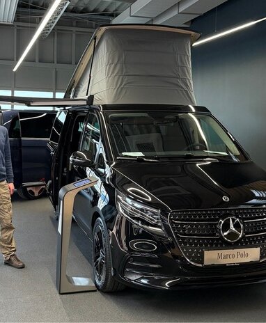 Mann steht neben einem schwarzen Mercedes Marco Polo im Showroom.