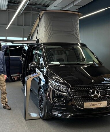 Mann steht neben einem schwarzen Mercedes Marco Polo im Showroom.