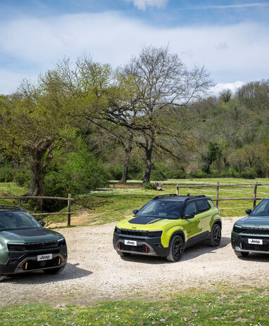 Drei Jeep-SUVs auf einem landschaftlichen Weg mit Bäumen im Hintergrund.
