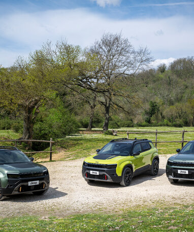 Drei Jeep-SUVs auf einem landschaftlichen Weg mit Bäumen im Hintergrund.