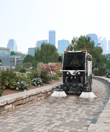 Eine CityCat VR17e Kehrmaschine von Bucher kehrt einen Gehweg in einem Park.