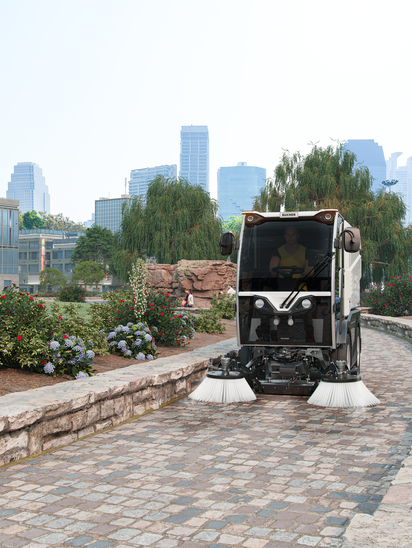 Eine CityCat VR17e Kehrmaschine von Bucher kehrt einen Gehweg in einem Park.
