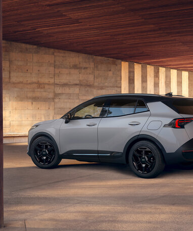 Grauer Kia Sportage SUV steht seitlich in einem architektonischen Innenhof aus Beton. | © Kia Österreich