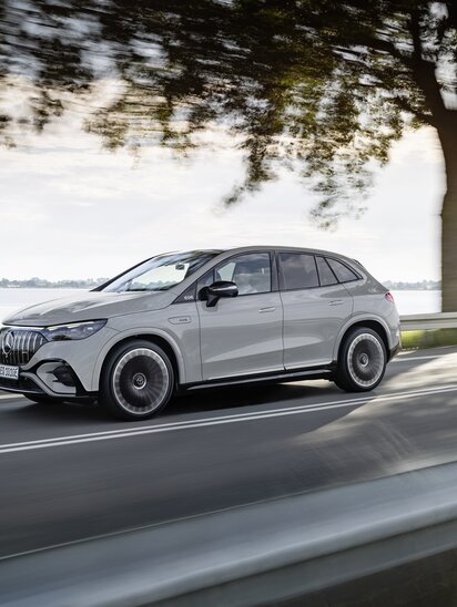 Ein Mercedes-AMG EQE SUV fährt entlang einer Straße mit Bäumen. | © Mercedes-Benz AG