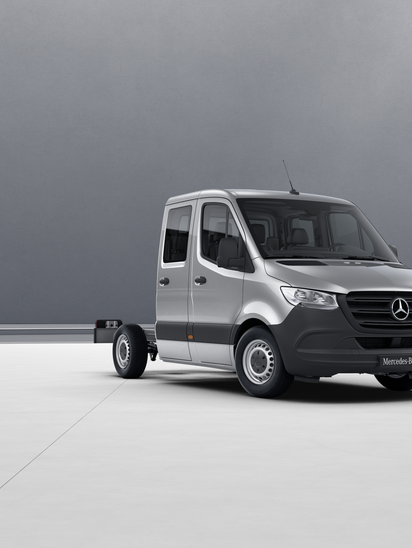 Silberner Mercedes-Benz Sprinter Fahrgestell mit Doppelkabine in leerem Raum.