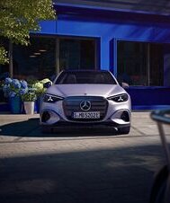 Frontansicht einer Mercedes-Benz C-Klasse Limousine vor einem blauen Gebäude mit Pflanzen im Hintergrund. | © Mercedes-Benz AG