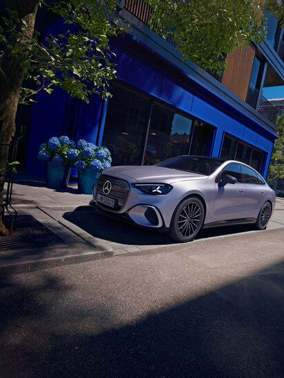 Mercedes-Benz Auto parkt auf einer städtischen Straße vor einem blauen Gebäude, umgeben von Pflanzen. | © Mercedes-Benz AG