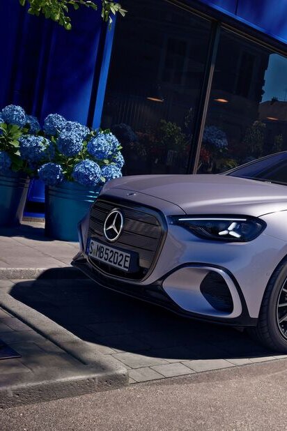 Mercedes-Benz Auto parkt auf einer städtischen Straße vor einem blauen Gebäude, umgeben von Pflanzen. | © Mercedes-Benz AG