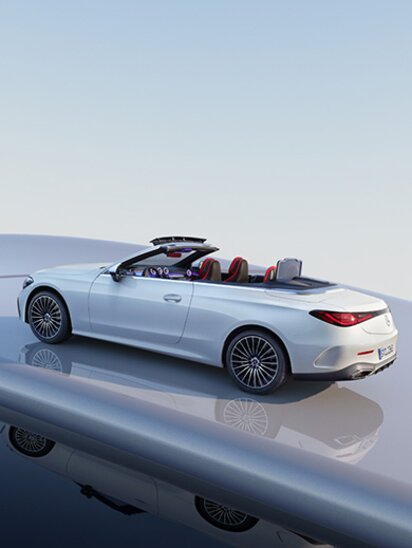 Weißes Mercedes-Benz CLE Cabrio mit offenem Verdeck auf glänzender Oberfläche.
