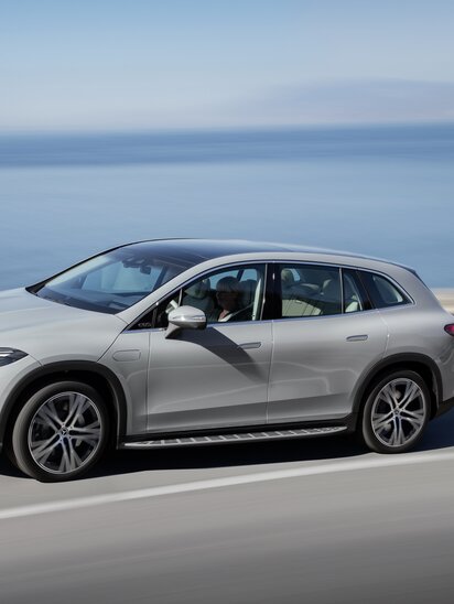 Silberner Mercedes-Benz EQS SUV fährt auf einer Küstenstraße mit Meer im Hintergrund. | © Mercedes-Benz AG