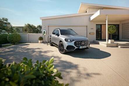 Ein silberner GLB mit EQ-Technologie steht vor einem Wohnhaus und lädt an einer Wallbox. | © Mercedes-Banz AG