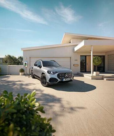 Ein silberner GLB mit EQ-Technologie steht vor einem Wohnhaus und lädt an einer Wallbox. | © Mercedes-Banz AG