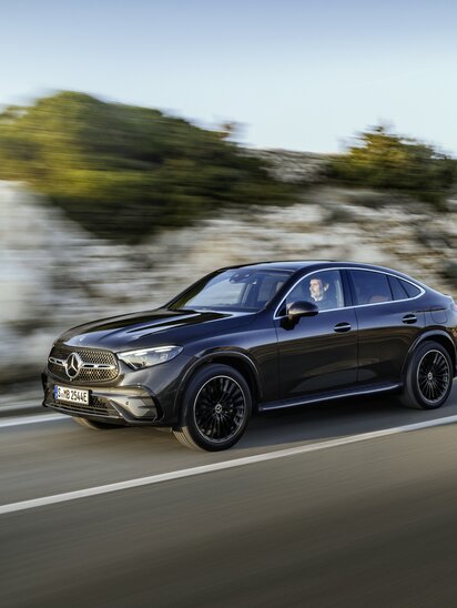 Schwarzes Mercedes-Benz GLC Coupé fährt auf einer Straße, umgeben von malerischer Landschaft. | © Mercedes-Benz AG