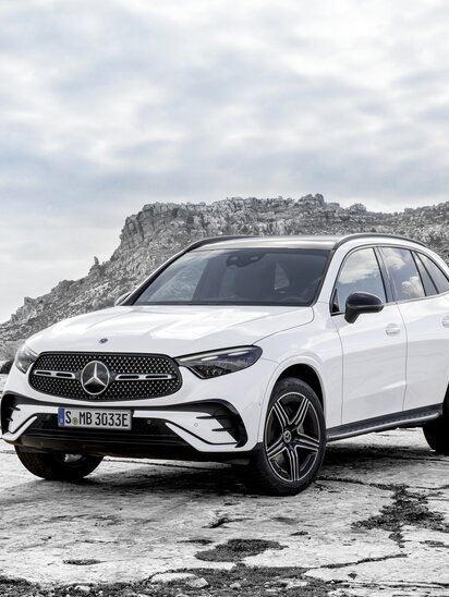 Weißer Mercedes-Benz GLC steht auf felsigem Untergrund vor bergiger Kulisse.