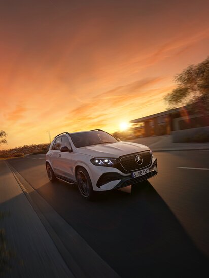 Ein weißer Mercedes-Benz GLE fährt bei Sonnenuntergang eine Straße entlang. | © Mercedes-Benz AG