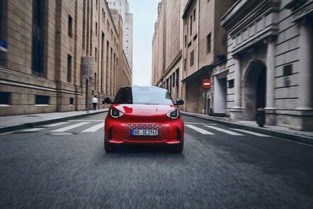 Der neue rote smart #2 fährt dynamisch durch eine städtische Straße.