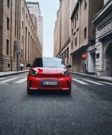 Der neue rote smart #2 fährt dynamisch durch eine städtische Straße.